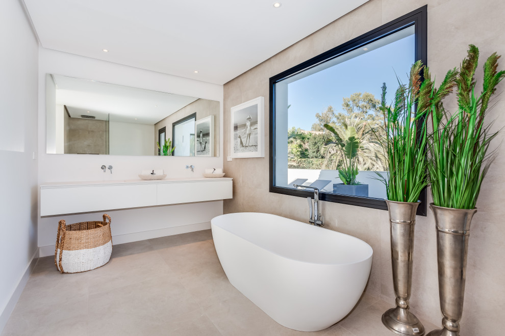 Photo of a contemporary bathroom in Other with flat-panel cabinets, white cabinets, a freestanding tub, beige tile, white walls, an undermount sink, beige floor, white benchtops, a double vanity and a floating vanity.