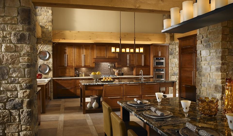 Eat-in kitchen - large rustic l-shaped ceramic tile and brown floor eat-in kitchen idea with an island, an undermount sink, raised-panel cabinets, medium tone wood cabinets, granite countertops, brown backsplash, glass tile backsplash and stainless steel appliances