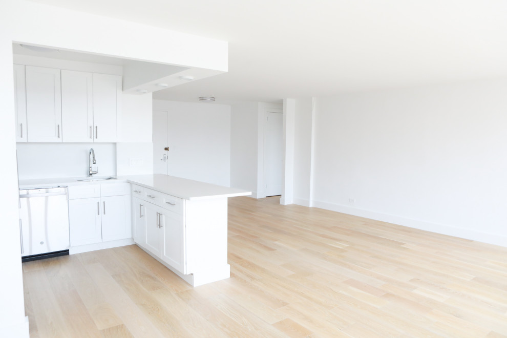 This is an example of a mid-sized modern u-shaped eat-in kitchen in Los Angeles with a drop-in sink, shaker cabinets, white cabinets, marble benchtops, white splashback, marble splashback, stainless steel appliances, bamboo floors, with island, brown floor and white benchtop.