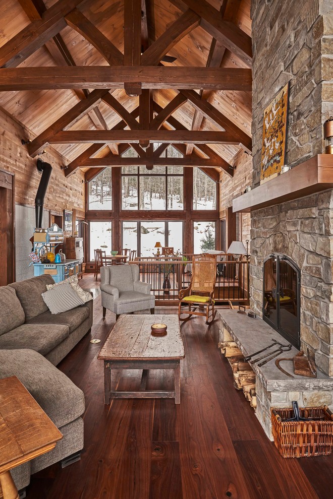 Inspiration for a mid-sized country open concept living room in Montreal with brown walls, dark hardwood floors, a wood stove, a stone fireplace surround, a freestanding tv and brown floor.