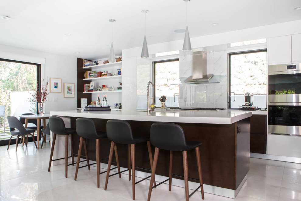 Design ideas for a large contemporary eat-in kitchen in Los Angeles with an undermount sink, flat-panel cabinets, quartz benchtops, white splashback, porcelain splashback, stainless steel appliances, limestone floors, with island, white benchtop, white cabinets and white floor.