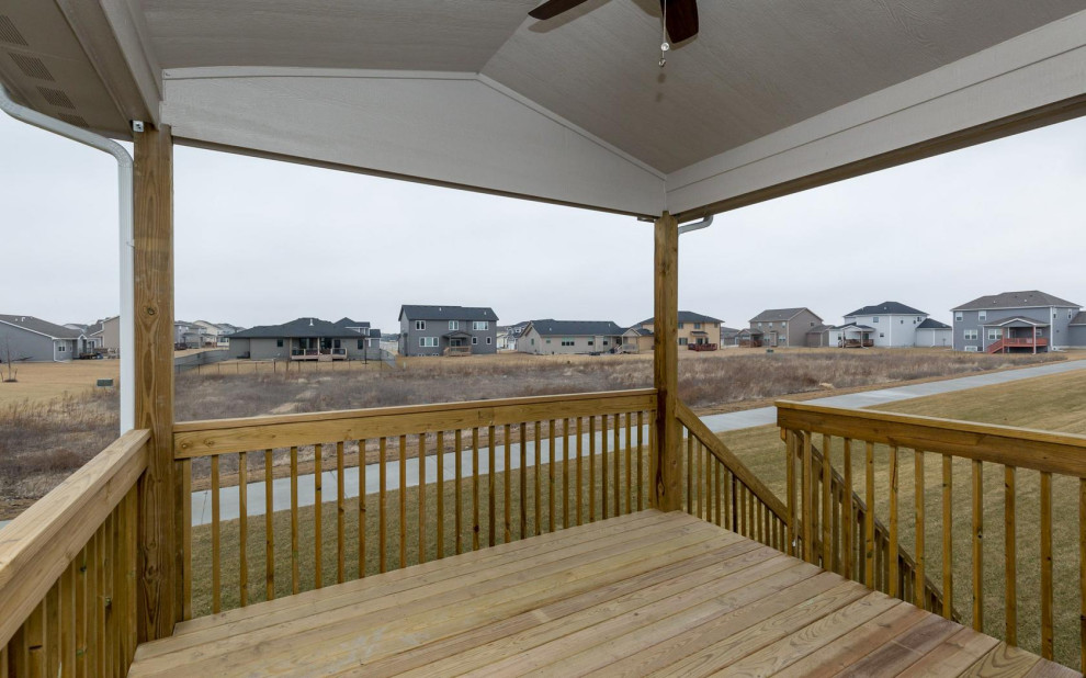 Example of a small transitional backyard deck design with a roof extension
