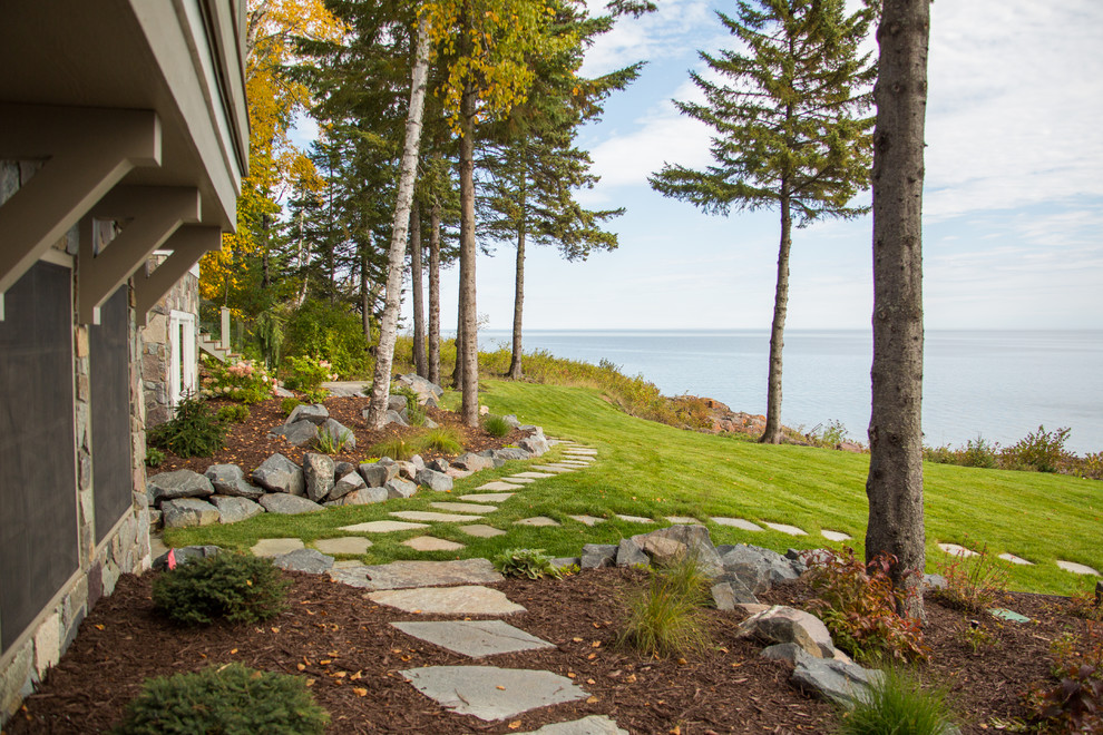 Beach style partial sun garden in Other with natural stone pavers.