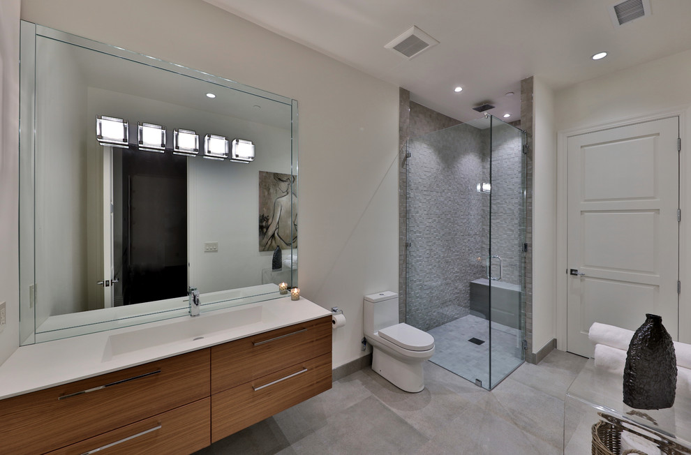 Photo of a large contemporary bathroom in Atlanta with furniture-like cabinets, brown cabinets, a corner shower, a one-piece toilet, gray tile, porcelain tile, white walls, porcelain floors, with a sauna, a drop-in sink, quartzite benchtops, grey floor, a hinged shower door and white benchtops.