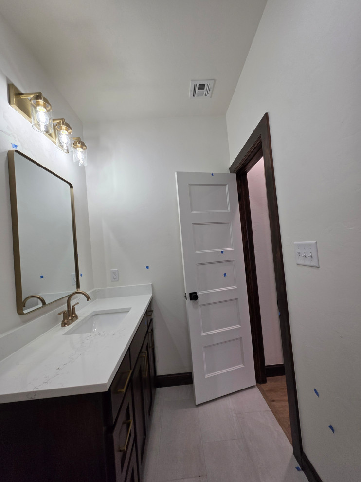 Upstairs vanity has quartz countertops and gold lighting accessories
