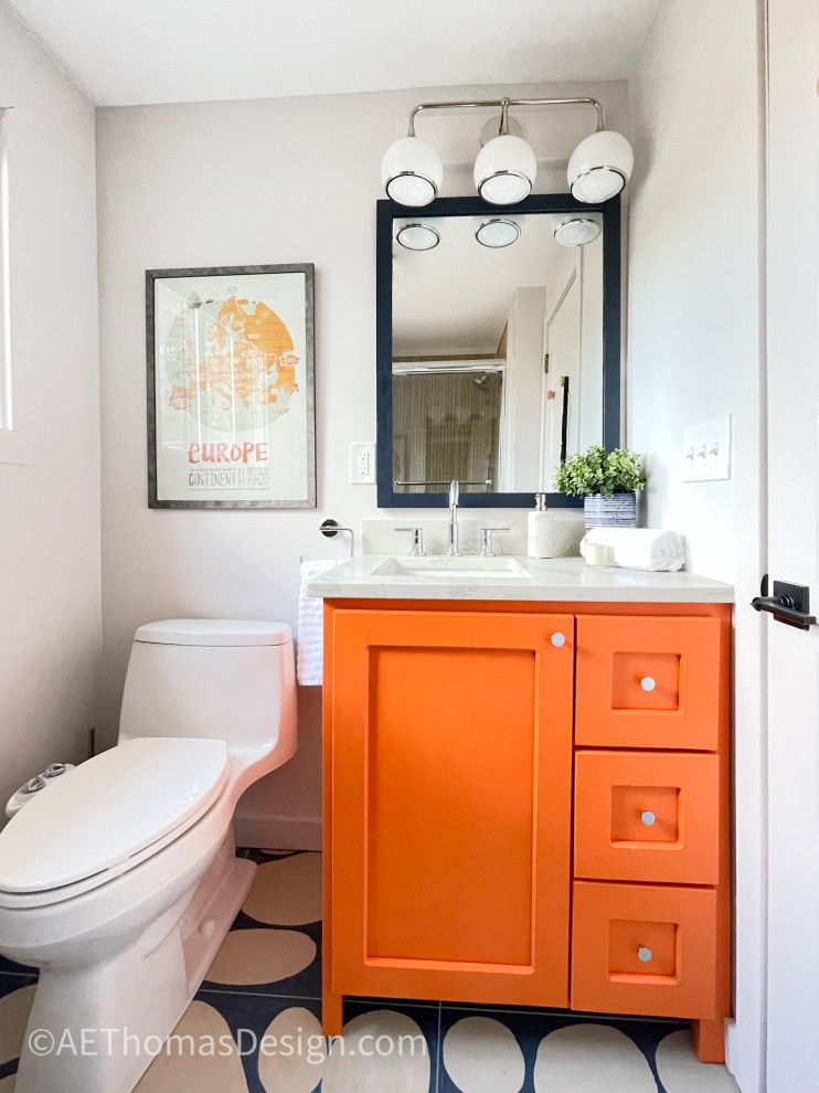 This is an example of a small modern bathroom in Burlington with recessed-panel cabinets, orange cabinets, an alcove bath, a shower/bath combination, a two-piece toilet, white walls, ceramic flooring, a submerged sink, engineered stone worktops, blue floors, a sliding door, white worktops, a single sink and a freestanding vanity unit.