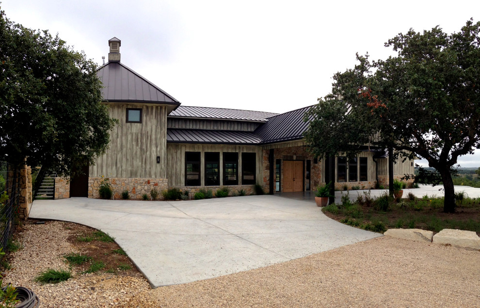 Photo of an expansive country two-storey grey exterior in Austin with wood siding and a gable roof.