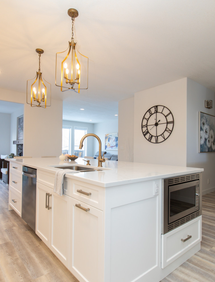 Large transitional l-shaped vinyl floor and gray floor open concept kitchen photo with an undermount sink, shaker cabinets, white cabinets, quartz countertops, white backsplash, marble backsplash, stainless steel appliances, an island and white countertops