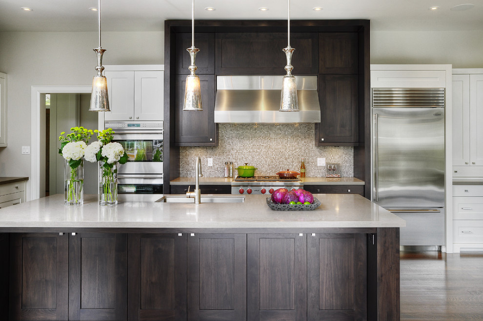 Transitional galley kitchen in Toronto with mosaic tile splashback, stainless steel appliances, an undermount sink, shaker cabinets, dark wood cabinets, brown splashback and solid surface benchtops.