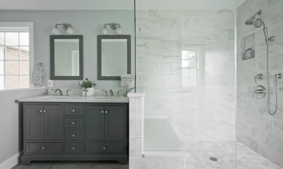Photo of a large transitional bathroom in DC Metro with furniture-like cabinets, grey cabinets, a two-piece toilet, white tile, porcelain tile, grey walls, porcelain floors, an undermount sink, engineered quartz benchtops, grey floor and white benchtops.