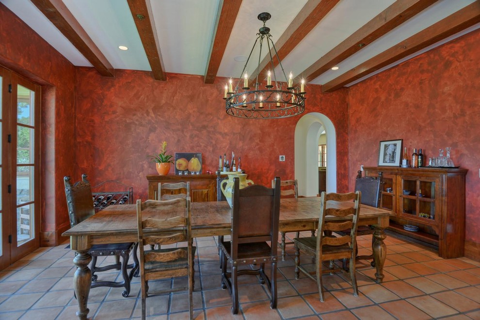 This is an example of a mediterranean dining room in San Francisco with red walls and terra-cotta floors.