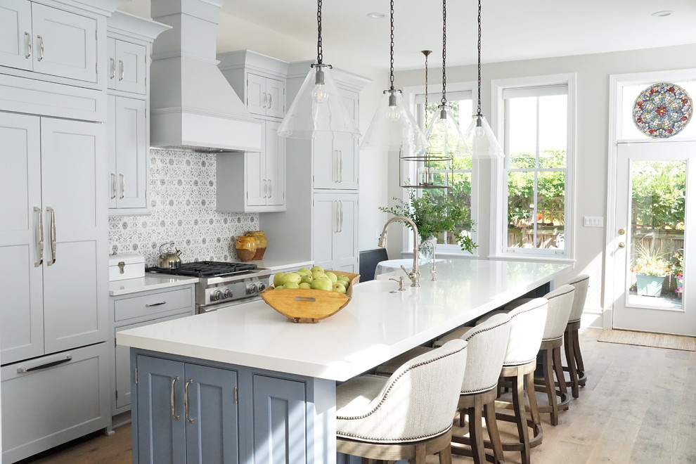 Eat-in kitchen - mid-sized transitional single-wall medium tone wood floor and beige floor eat-in kitchen idea with a farmhouse sink, shaker cabinets, gray cabinets, quartzite countertops, gray backsplash, marble backsplash, paneled appliances, an island and white countertops