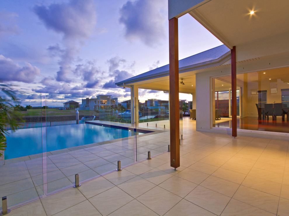 This is an example of a mid-sized beach style backyard patio in Brisbane with a water feature, tile and a roof extension.