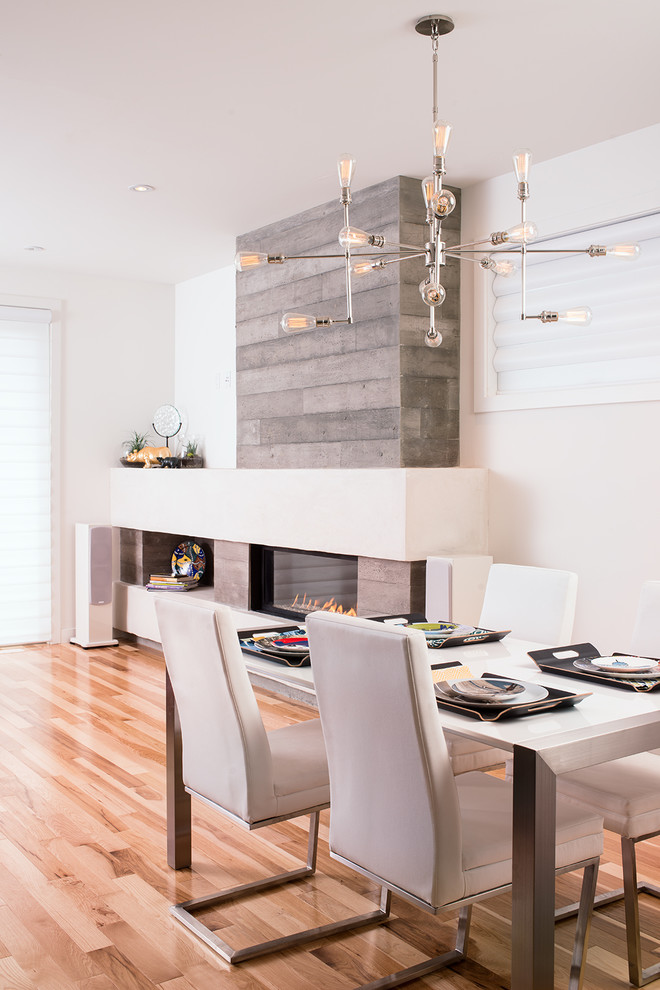 Inspiration for a contemporary dining room in Calgary with white walls, medium hardwood floors, a ribbon fireplace and a concrete fireplace surround.