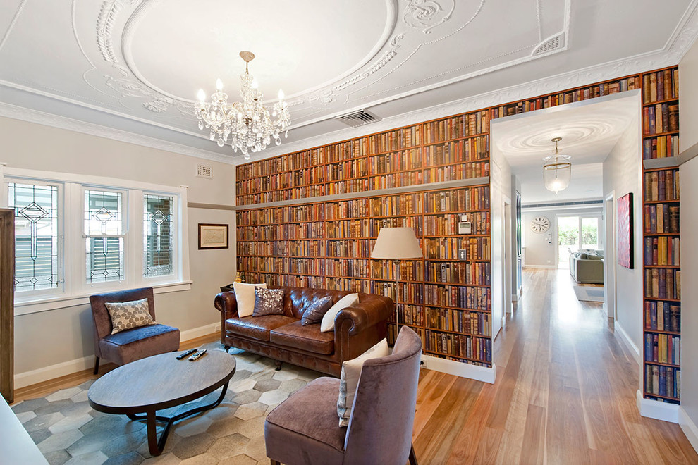 This is an example of a mid-sized traditional enclosed living room in Sydney with multi-coloured walls, medium hardwood floors, a built-in media wall, a library and brown floor.