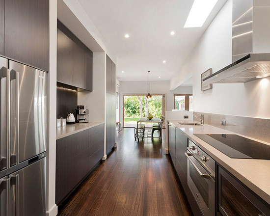 Photo of a mid-sized contemporary separate kitchen in Melbourne with flat-panel cabinets, dark wood cabinets, quartz benchtops, beige splashback, stainless steel appliances, a double-bowl sink and dark hardwood floors.