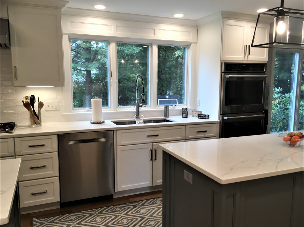 Large transitional galley light wood floor and brown floor eat-in kitchen photo in Boston with an undermount sink, shaker cabinets, white cabinets, quartz countertops, white backsplash, subway tile backsplash, stainless steel appliances, two islands and white countertops
