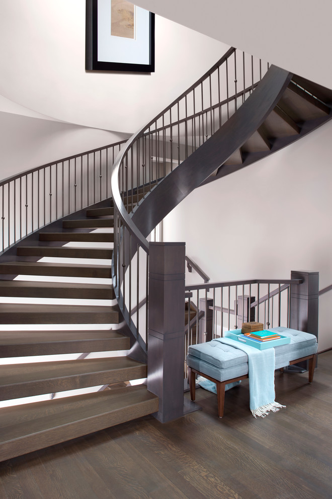 This is an example of a large transitional wood curved staircase in Calgary with open risers.