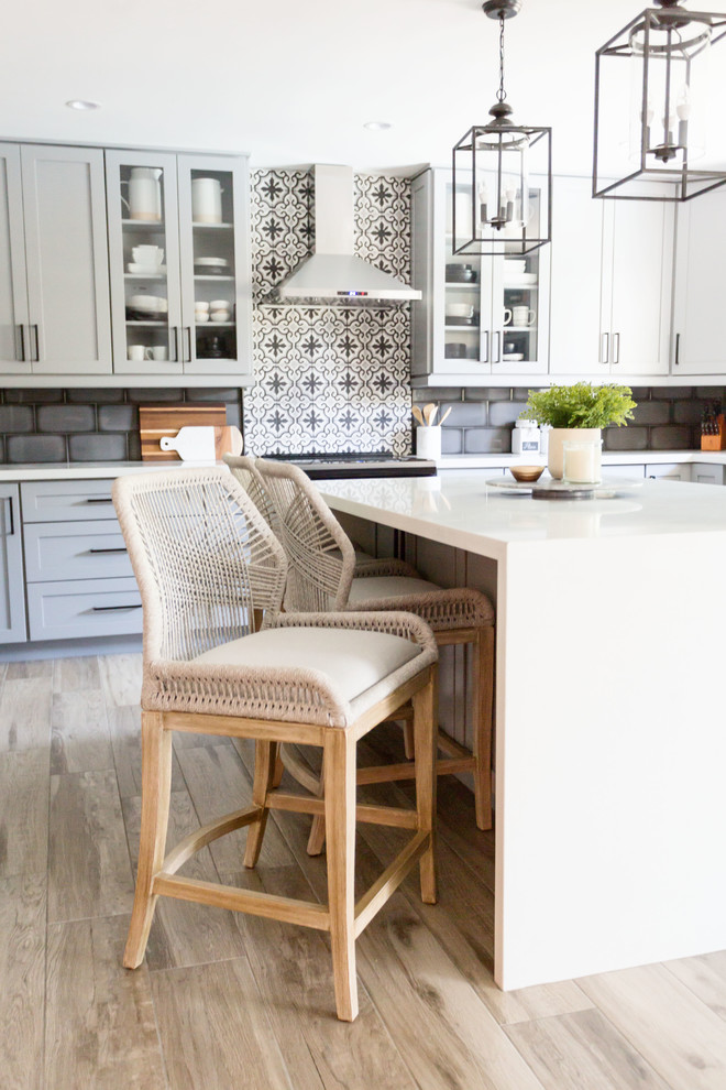 Mid-sized transitional u-shaped light wood floor and gray floor eat-in kitchen photo in Phoenix with an undermount sink, recessed-panel cabinets, gray cabinets, quartz countertops, multicolored backsplash, ceramic backsplash, stainless steel appliances, an island and white countertops