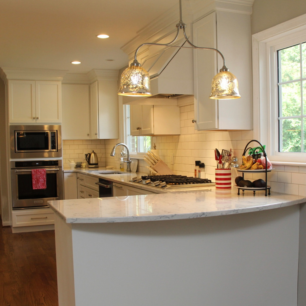 Example of a mid-sized transitional u-shaped dark wood floor and brown floor eat-in kitchen design in Baltimore with an undermount sink, flat-panel cabinets, white cabinets, granite countertops, white backsplash, porcelain backsplash, stainless steel appliances, a peninsula and white countertops