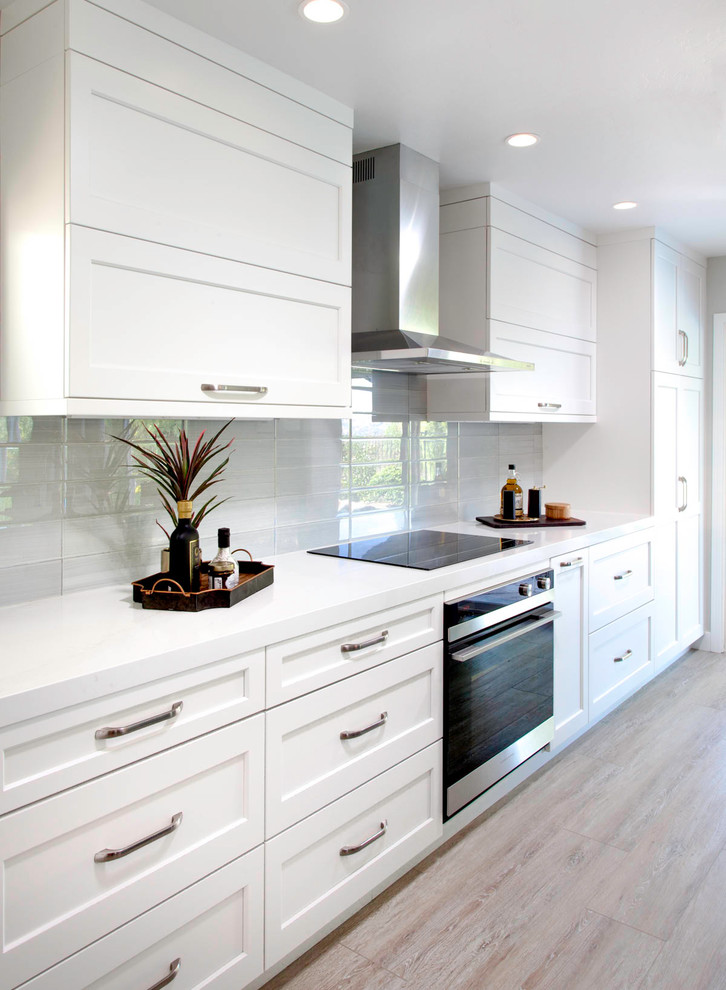 Open concept kitchen - large transitional l-shaped vinyl floor and beige floor open concept kitchen idea in San Diego with an undermount sink, shaker cabinets, white cabinets, quartz countertops, gray backsplash, ceramic backsplash, paneled appliances, an island and white countertops