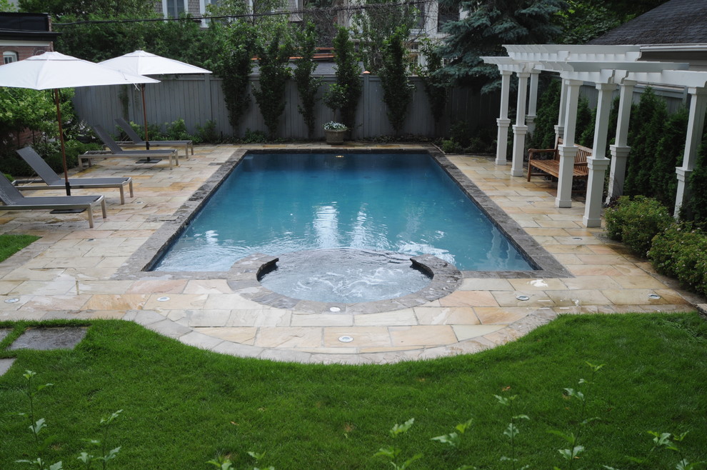 Ejemplo de piscina con fuente tradicional de tamaño medio rectangular en patio trasero con adoquines de piedra natural