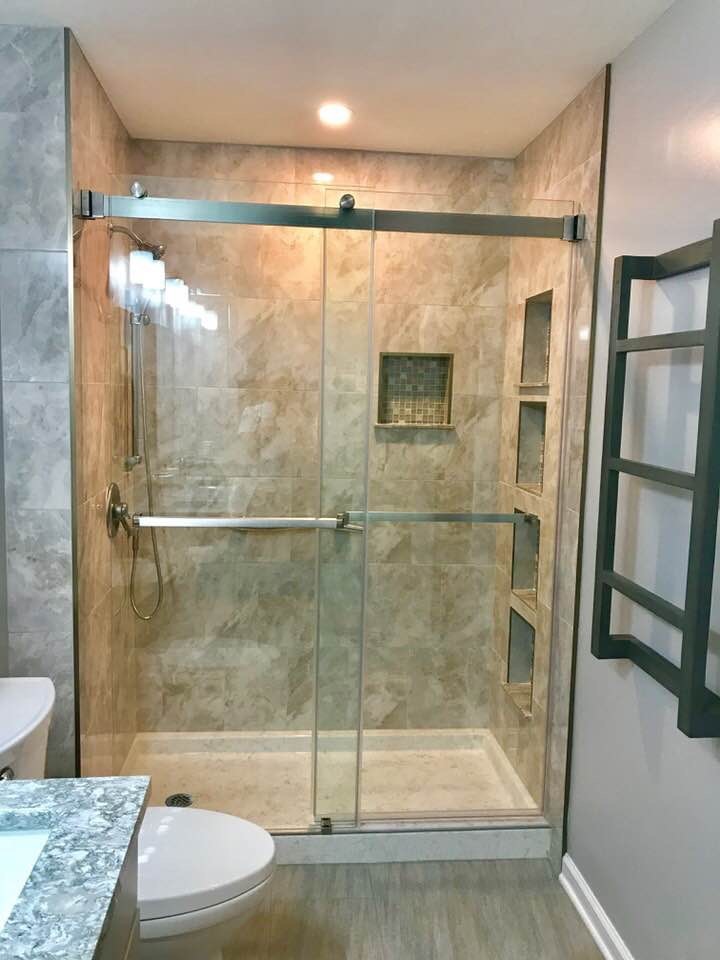This is an example of a mid-sized transitional master bathroom in New York with shaker cabinets, grey cabinets, an alcove shower, a two-piece toilet, brown tile, ceramic tile, beige walls, ceramic floors, an undermount sink, engineered quartz benchtops, beige floor, a sliding shower screen and beige benchtops.