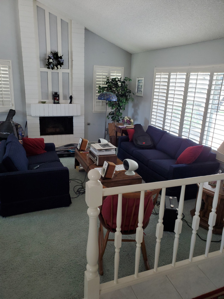 Mittelgroßes, Offenes Klassisches Wohnzimmer mit blauer Wandfarbe, Teppichboden, Kamin, Kaminumrandung aus Backstein, blauem Boden und gewölbter Decke in San Diego