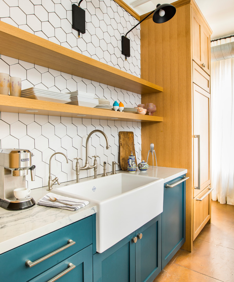 Photo of a contemporary galley open plan kitchen in Los Angeles with a farmhouse sink, shaker cabinets, turquoise cabinets, quartz benchtops, white splashback, stainless steel appliances, porcelain floors, a peninsula, multi-coloured floor and white benchtop.