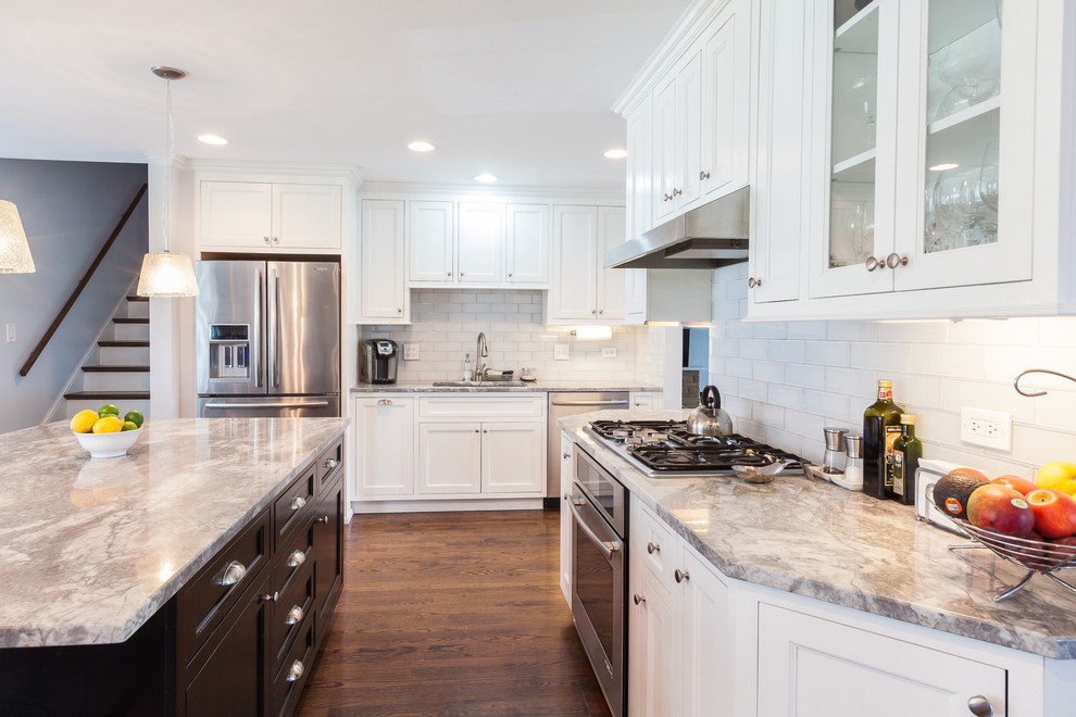 This is an example of a large contemporary l-shaped open plan kitchen in Chicago with an undermount sink, shaker cabinets, white cabinets, quartzite benchtops, white splashback, stainless steel appliances, medium hardwood floors and with island.