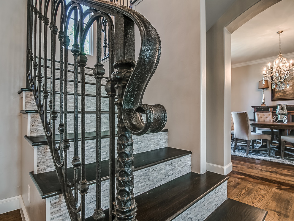 Photo of a large traditional wood l-shaped staircase in Oklahoma City with travertine risers and metal railing.