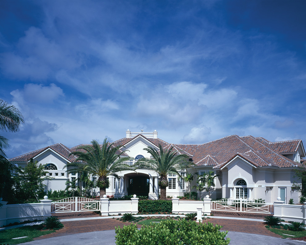 This is an example of an expansive traditional two-storey stucco white exterior in Miami with a hip roof.