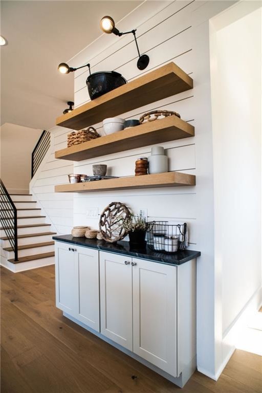 Open concept kitchen - mid-sized transitional l-shaped light wood floor and beige floor open concept kitchen idea in Miami with an undermount sink, shaker cabinets, white cabinets, onyx countertops, white backsplash, wood backsplash, stainless steel appliances, an island and black countertops
