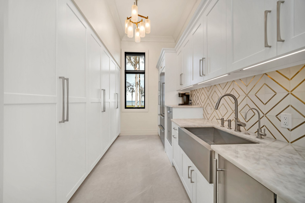 Inspiration for a large transitional galley enclosed kitchen remodel in Orlando with a farmhouse sink, shaker cabinets, white cabinets, stainless steel appliances and an island