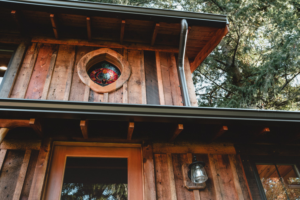 Esempio della micro casa piccola multicolore rustica a un piano con rivestimento in legno, tetto a capanna, copertura in metallo o lamiera, tetto nero e pannelli e listelle di legno