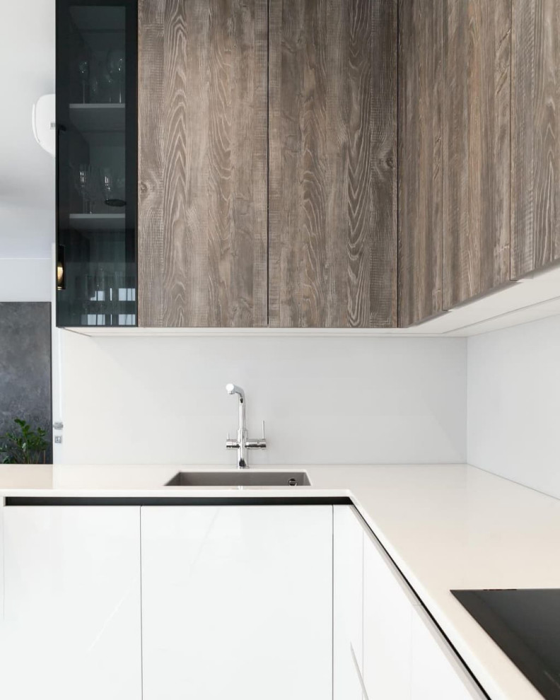 Photo of a large scandinavian u-shaped eat-in kitchen in Moscow with an undermount sink, flat-panel cabinets, white cabinets, solid surface benchtops, white splashback, stainless steel appliances, ceramic floors, a peninsula, beige floor and white benchtop.