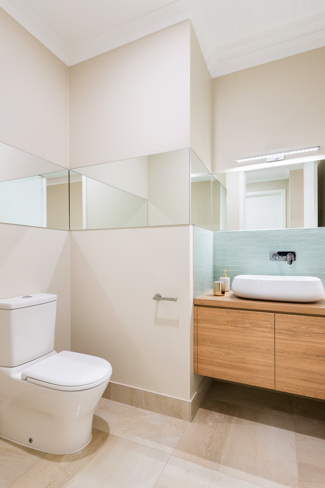 Mid-sized contemporary powder room in Other with furniture-like cabinets, light wood cabinets, a one-piece toilet, beige tile, ceramic tile, beige walls, ceramic floors, a vessel sink, laminate benchtops and beige floor.