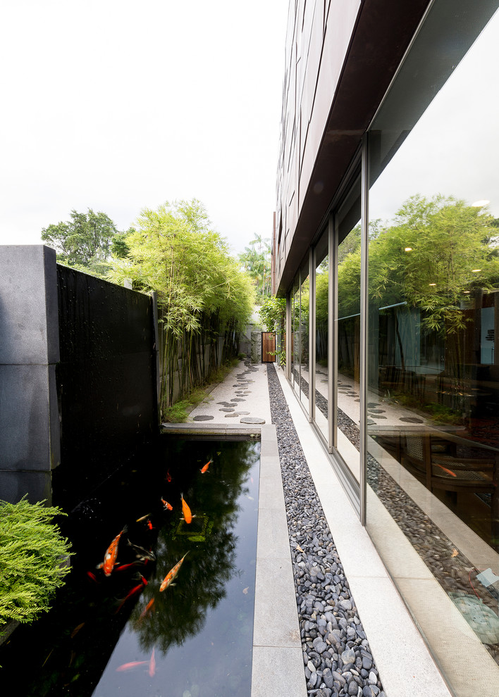 Contemporary partial sun garden in Singapore with a water feature and natural stone pavers.