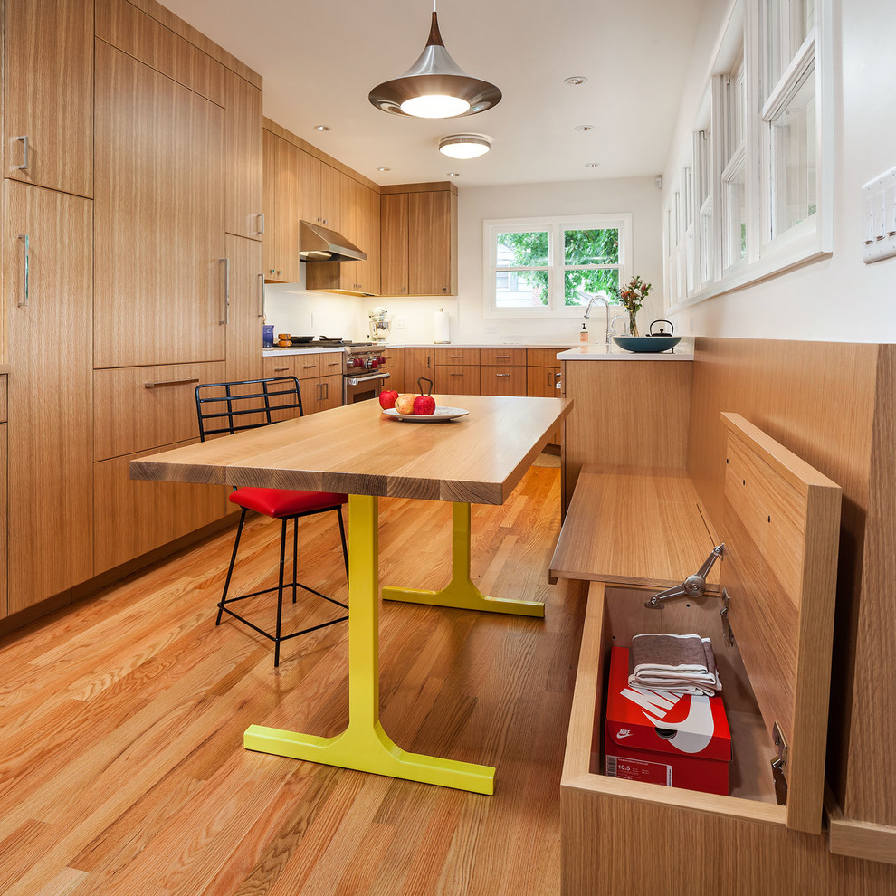 This is an example of a contemporary u-shaped eat-in kitchen in Portland with flat-panel cabinets, medium wood cabinets, white splashback, panelled appliances, medium hardwood floors and no island.