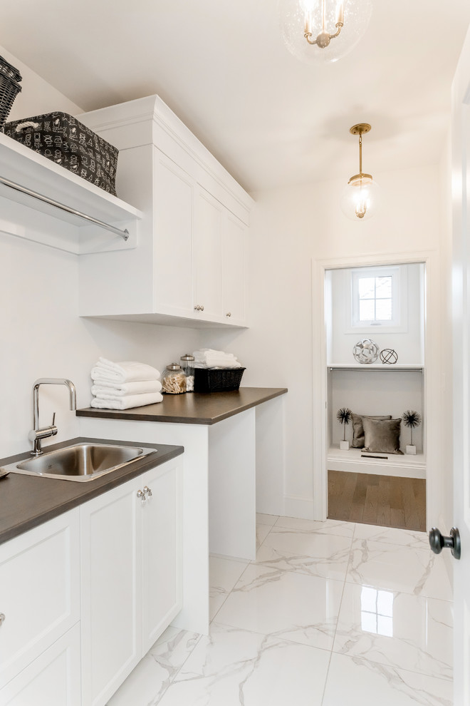 Inspiration for a small transitional single-wall dedicated laundry room in Other with a drop-in sink, shaker cabinets, white cabinets, laminate benchtops, white walls, marble floors, a side-by-side washer and dryer and white floor.