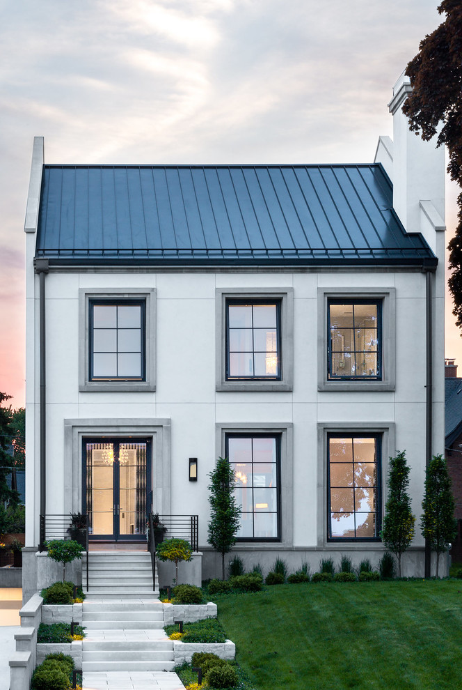 This is an example of a transitional two-storey white house exterior in Chicago with a gable roof and a metal roof.