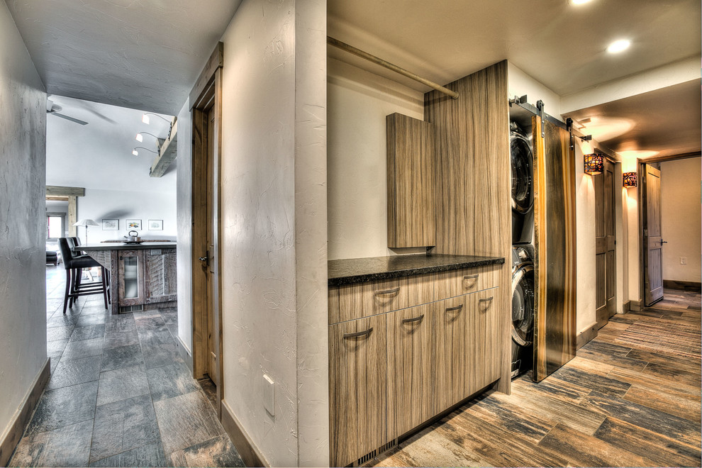 Example of a mountain style single-wall ceramic tile laundry closet design in Denver with flat-panel cabinets, gray cabinets, granite countertops, gray walls and a stacked washer/dryer