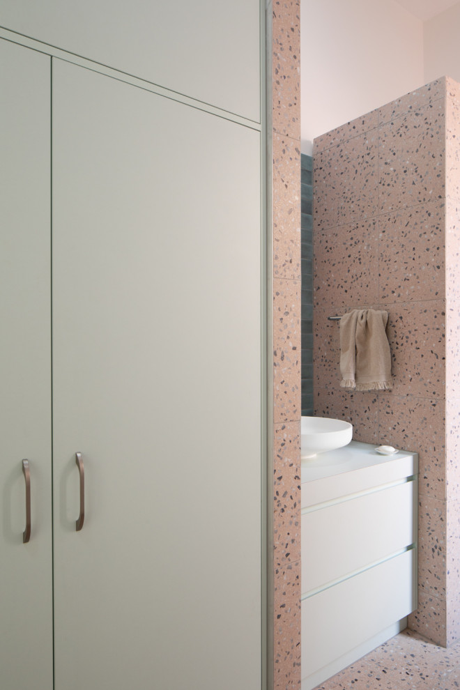 На фото: главная ванная комната среднего размера со стиральной машиной в стиле фьюжн с плоскими фасадами, зелеными фасадами, накладной ванной, открытым душем, раздельным унитазом, розовой плиткой, каменной плиткой, розовыми стенами, полом из терраццо, настольной раковиной, столешницей из ламината, розовым полом, открытым душем, зеленой столешницей, тумбой под одну раковину и встроенной тумбой с