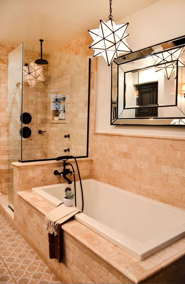 Photo of a mid-sized mediterranean master bathroom in Los Angeles with beaded inset cabinets, brown cabinets, a drop-in tub, a corner shower, a one-piece toilet, beige tile, travertine, white walls, porcelain floors, an undermount sink, solid surface benchtops, multi-coloured floor, a hinged shower door and grey benchtops.