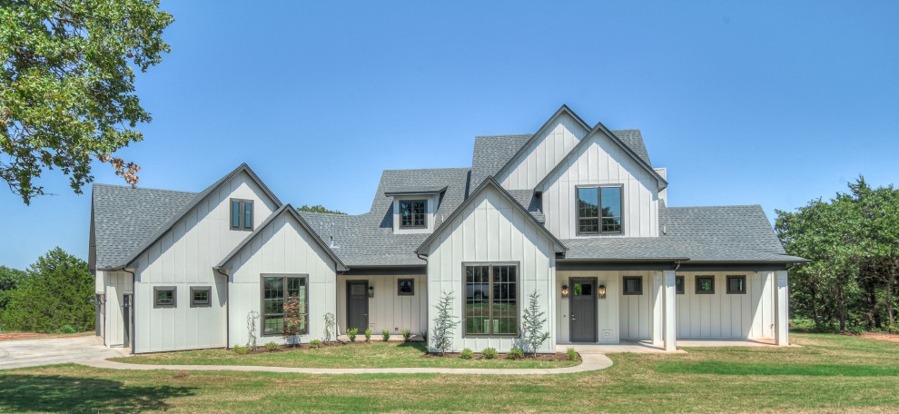 Example of a large cottage white two-story vinyl and shingle exterior home design in Oklahoma City with a shingle roof and a gray roof