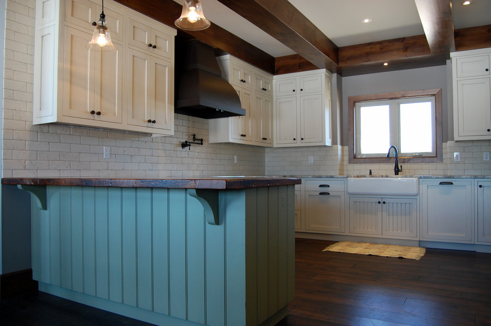 Photo of a large country u-shaped kitchen in Toronto with a farmhouse sink, recessed-panel cabinets, distressed cabinets, wood benchtops, white splashback, dark hardwood floors and a peninsula.