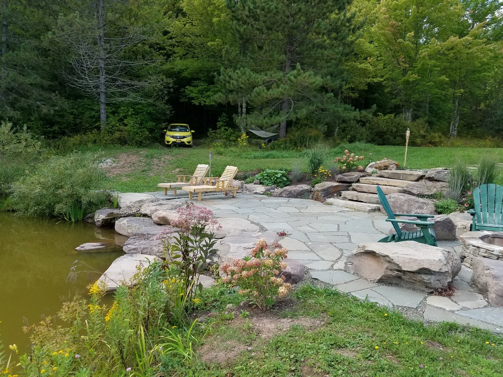 Design ideas for a large country backyard patio in New York with a fire feature, natural stone pavers and no cover.