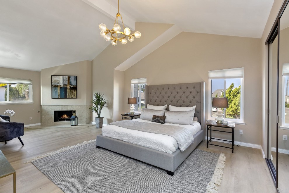 Design ideas for a large traditional master bedroom in San Diego with beige walls, vinyl flooring, a corner fireplace, a tiled fireplace surround and a vaulted ceiling.