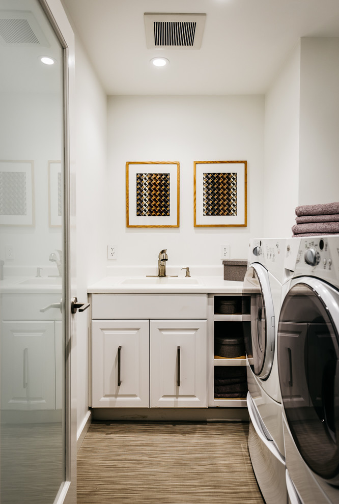This is an example of a traditional single-wall dedicated laundry room in San Francisco with an integrated sink, raised-panel cabinets, white cabinets, white walls and a side-by-side washer and dryer.
