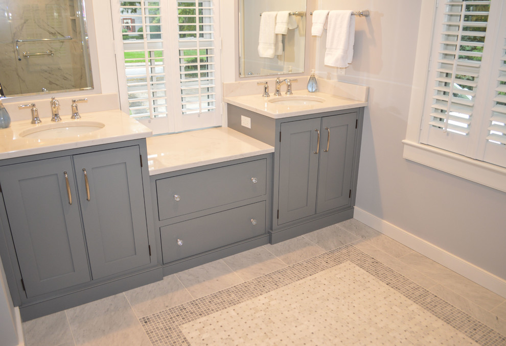 Photo of a mid-sized transitional master bathroom in Cleveland with beaded inset cabinets, blue cabinets, a corner shower, a two-piece toilet, gray tile, porcelain tile, grey walls, mosaic tile floors, an undermount sink, engineered quartz benchtops, multi-coloured floor and a hinged shower door.